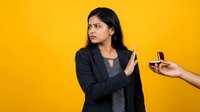 Young Indian businesswoman in black blazer refusing cigarette offer with hand gesture against bright yellow background for health awareness campaigns.
