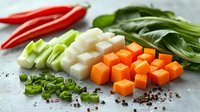 Fresh diced vegetables and seafood ingredients on gray background with scattered peppercorns, ready for Asian cuisine preparation and cooking.