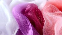 Colorful flowing fabric ribbons in pink purple coral shades with soft texture and gentle curves creating elegant waves for fashion design projects.
