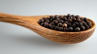 Aromatic black peppercorns in wooden spoon on light background, macro food photography for cooking, seasoning and spice marketing materials.