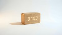 Modern wooden digital alarm clock displaying 07:00 on white background, isolated for design use on product mockups and home decor projects.