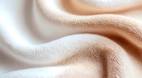 Soft beige silk fabric with gentle folds and waves creating an elegant textural background pattern. Luxurious macro photography shows fine textile details.