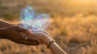 Hands gently holding glowing translucent butterfly with rainbow wings at golden sunset, symbolizing hope, transformation and spiritual connection.