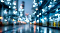 Defocused urban night cityscape with blue bokeh lights reflecting on wet pavement, creating atmospheric mood for background designs.