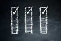 Three white chalk checkboxes with checkmarks drawn on black chalkboard background, representing completed tasks or successful achievement.