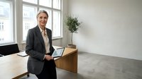 Professional mature businesswoman with gray hair holding tablet in modern minimalist office space with natural light and plant decor for corporate presentations.