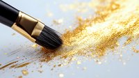 Makeup brush sweeping through scattered gold glitter powder on white surface, creating shimmering trail of metallic sparkles. Professional cosmetics application.