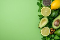 Fresh avocado, lemon, lime, chia seeds and mint leaves arranged on green background with copy space for healthy eating and nutrition concepts.