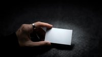 Hand holding blank white business card on dark textured surface for corporate branding and professional identity design mockup template.