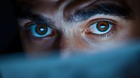 Close-up portrait of young person with striking heterochromia eyes, one blue and one brown, gazing intensely at camera with dramatic lighting and shadows.