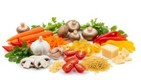 Fresh organic vegetables, pasta, cheese and herbs arranged on white background for healthy cooking and meal preparation.