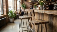 Wooden bar stools with metal legs positioned at rustic wooden counter in modern cafe interior with brick walls and potted plants for hospitality design.
