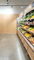 Modern grocery store produce section with fresh fruits and vegetables displayed in wooden shelving units under track lighting for retail design.