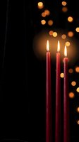 Red candles burning with warm flames against dark background with golden bokeh lights creating cozy atmospheric mood for relaxation and meditation.