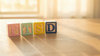 PTSD wooden blocks with letters on wooden surface in sunlit room, suitable for mental health awareness and educational materials.