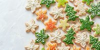 Maple leaf sugar cookies decorated with green, orange and white royal icing on light background. Seasonal autumn baking with detailed piping patterns.
