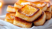 Caramelized grilled mochi squares with golden-brown crispy exterior and soft chewy interior, stacked on white cloth napkin, close-up food photography.