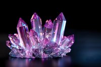 Pink and purple crystal cluster formation with translucent points and facets glowing against dark background, mineral specimen with geometric shapes and light reflections.