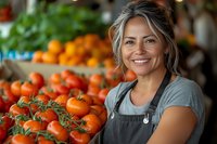 Smiling mature Hispanic female farmer in apron standing near fresh organic tomatoes at local market stall, representing sustainable agriculture and farm-to-table concept.