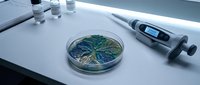 Laboratory petri dish with green bacterial culture sample on white table with digital thermometer and test tubes for microbiology research and scientific analysis.