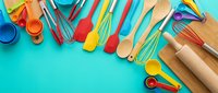 Colorful kitchen utensils and baking tools arranged on turquoise background with copy space for culinary design projects and cooking content.