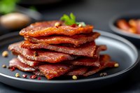 Stack of crispy cooked bacon strips on dark plate with herbs and spices for breakfast or cooking ingredients.