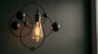 Vintage-style pendant lighting fixture with Edison bulb and black metal spheres suspended from curved arms, suitable for interior design and home decor projects.