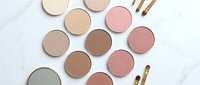 Professional makeup palette with neutral eyeshadow shades in pink, brown, beige tones and cosmetic brushes on marble background for beauty routine.