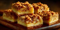 Golden crumb cake bars with nuts and caramel filling stacked on wooden board. Homemade dessert squares with crumbly topping for bakery menu and sweet treats.
