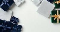 Wrapped gift boxes in navy, silver, and green with gold and blue ribbons arranged on white background, suitable for holiday, celebration, and seasonal marketing materials.