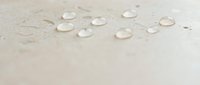 Water droplets on beige surface creating natural moisture pattern for spa wellness and skincare concepts.
