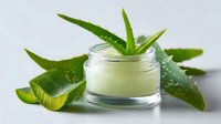 Fresh aloe vera cream in glass jar with cut pieces of natural plant leaves on light background, organic skincare and beauty product for moisturizing.