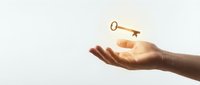 Open hand reaching for floating golden key against soft light background symbolizing opportunity, success, and unlocking potential in business.