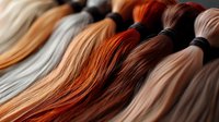 Colorful embroidery thread skeins in warm autumn tones arranged in rows. Natural fiber craft supplies for needlework, cross stitch and textile projects.