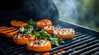 Grilled sweet potatoes with herbs on barbecue grill, steam rising from caramelized slices with charred grill marks, perfect for summer cookout recipes.