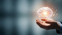 Human hands holding glowing brain with neural connections and light particles representing artificial intelligence, innovation and mental health concepts.