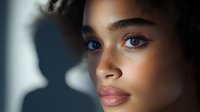 Young mixed race woman with freckles and blue eyes in dramatic lighting, close up beauty portrait showing natural makeup and glowing skin. Soft side illumination.