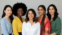 Diverse group of five professional women smiling together in colorful business attire representing teamwork and workplace diversity.