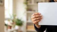 Person holding blank white card or paper in hand, ideal for business messaging, advertising copy, promotional campaigns, and corporate communications.