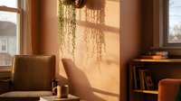 Cozy reading corner with warm sunlight streaming through window creating beautiful shadow patterns on wall. Comfortable armchair and books create peaceful atmosphere.