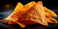 Crispy golden corn tortilla chips with textured surface arranged on dark slate surface, perfect for snacking, appetizers and Mexican cuisine presentations.