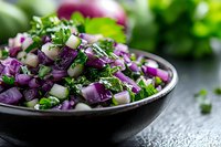 Fresh chopped purple cabbage salad with cucumber and herbs in black ceramic bowl on dark background, healthy vegetarian food closeup.