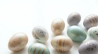 Colorful decorated Easter eggs with natural patterns and stripes scattered on white background for spring holiday celebrations and seasonal designs.