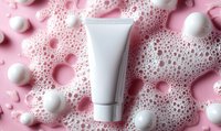 White blank cosmetic tube on pink background with foam bubbles and pearls, mockup for skincare product packaging design and beauty branding.