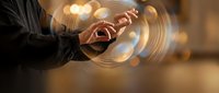 Business professional using smartphone with glowing digital circles and warm bokeh lights creating modern technology communication concept.
