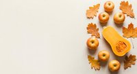 Autumn harvest composition with orange pumpkin, golden apples and oak leaves on neutral background. Seasonal fall arrangement for thanksgiving decor.