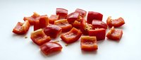 Fresh red bell pepper diced into small cubes on white background, ready for cooking and meal preparation in kitchen recipes.