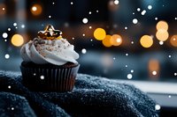 Chocolate cupcake with white frosting and gold star topper on snowy surface with bokeh lights, festive holiday dessert for bakery, celebration, and food photography.