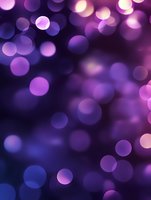 Purple and blue bokeh lights creating dreamy defocused background with glowing circular shapes, suitable for festive designs and romantic layouts.