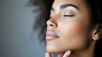 Close up profile portrait of young African American woman with natural curly hair, closed eyes, and serene expression showing wellness and beauty skincare concept.